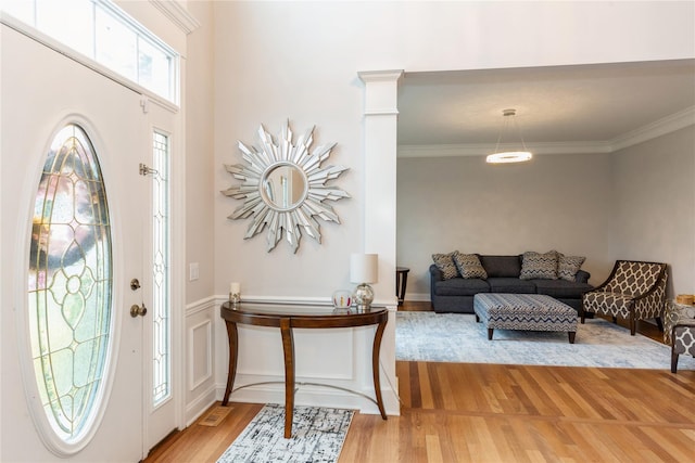 foyer entrance featuring wood-type flooring, ornate columns, and crown molding