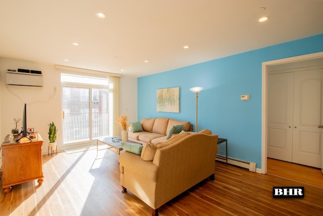 living room featuring a wall mounted air conditioner, hardwood / wood-style flooring, and a baseboard heating unit