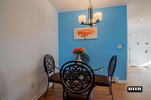 dining space featuring wood-type flooring, a notable chandelier, and a baseboard heating unit