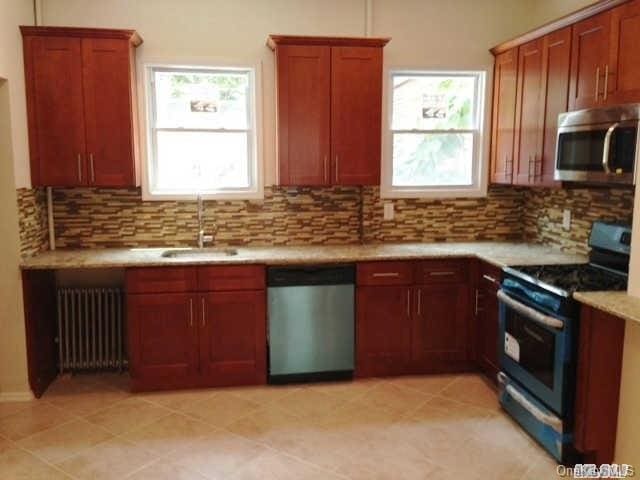 kitchen featuring radiator, plenty of natural light, stainless steel appliances, and sink