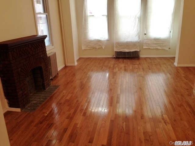 unfurnished living room with radiator, plenty of natural light, light hardwood / wood-style floors, and a brick fireplace