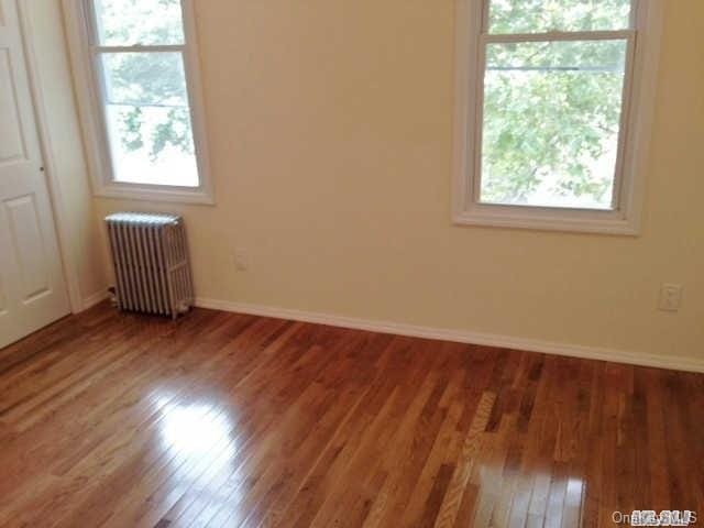 empty room with hardwood / wood-style flooring and radiator