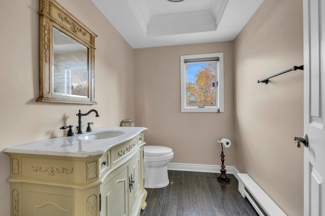 bathroom with vanity, a tray ceiling, baseboard heating, hardwood / wood-style floors, and toilet