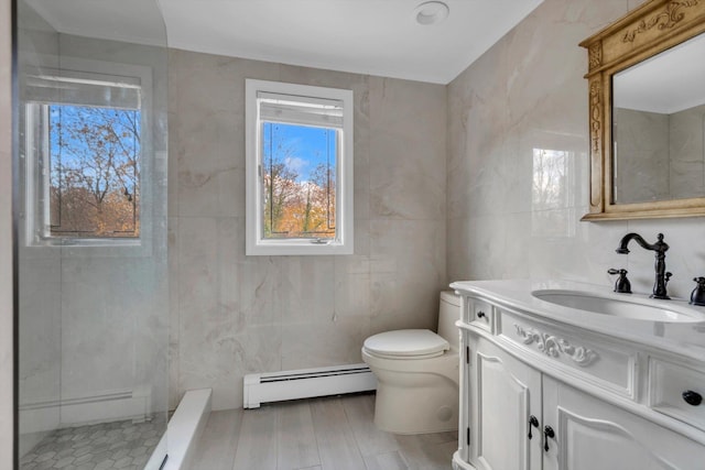 bathroom with a baseboard radiator, a shower, toilet, vanity, and tile walls