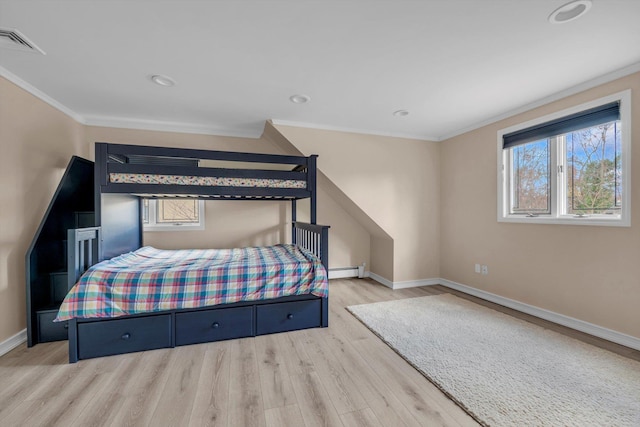 bedroom featuring a baseboard heating unit, crown molding, and light hardwood / wood-style flooring