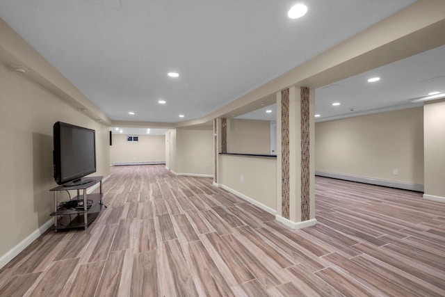 basement featuring baseboard heating and light hardwood / wood-style flooring