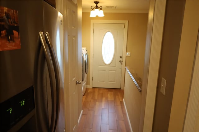 entryway featuring a notable chandelier, washing machine and clothes dryer, and light hardwood / wood-style flooring