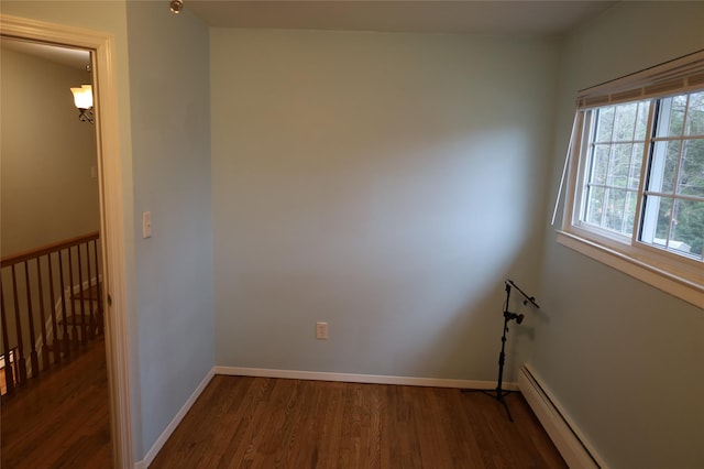 unfurnished room with baseboard heating and dark hardwood / wood-style flooring