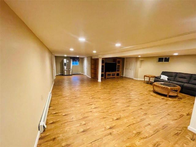 living room featuring light wood-type flooring, baseboard heating, and built in shelves