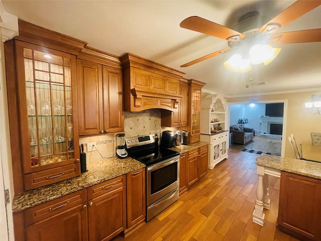 kitchen with light wood-type flooring, backsplash, electric range, and light stone counters