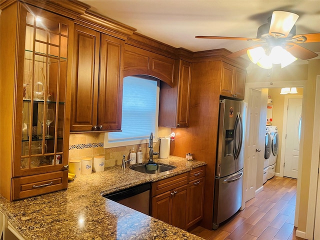 kitchen with washer and dryer, sink, stone counters, and stainless steel appliances