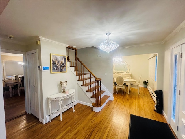 interior space featuring a baseboard heating unit, ornamental molding, wood-type flooring, and a notable chandelier