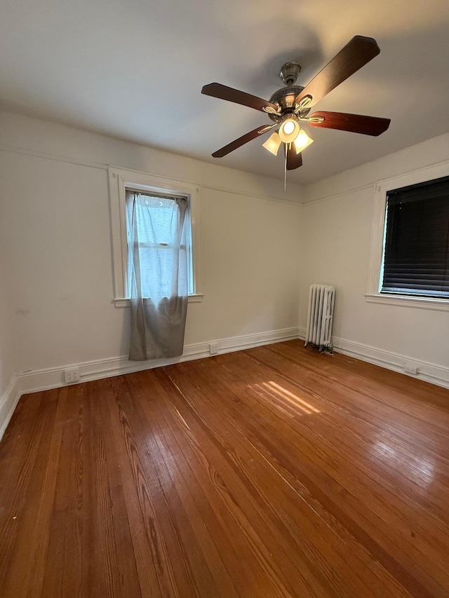 spare room with radiator, hardwood / wood-style floors, and ceiling fan