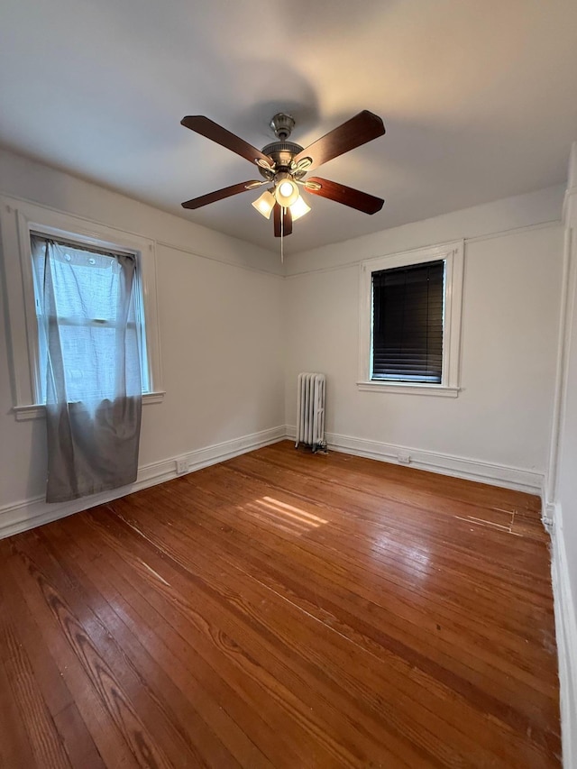 spare room with hardwood / wood-style floors, radiator heating unit, and ceiling fan