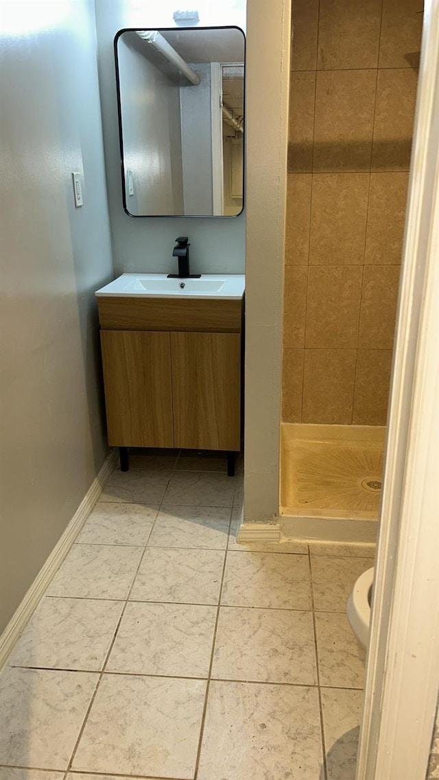 bathroom featuring tile patterned flooring, vanity, tiled shower, and toilet