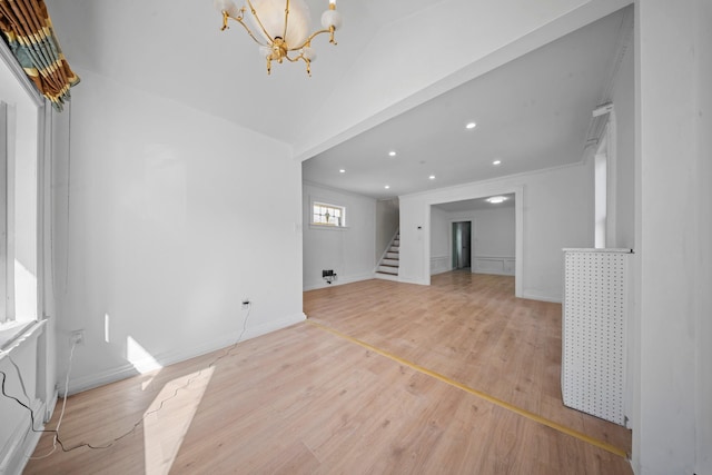 unfurnished living room with lofted ceiling, a notable chandelier, and light hardwood / wood-style flooring