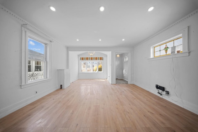 unfurnished living room featuring plenty of natural light, a notable chandelier, and light hardwood / wood-style flooring