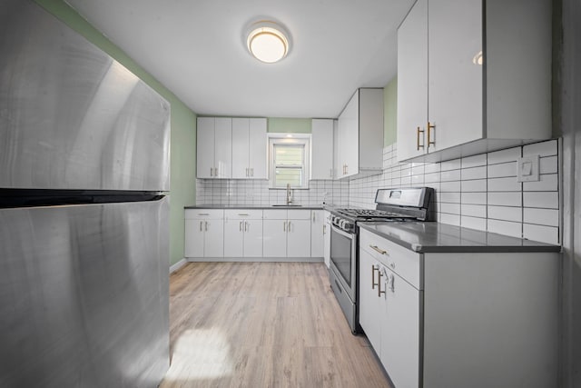 kitchen featuring appliances with stainless steel finishes, light hardwood / wood-style flooring, white cabinets, and decorative backsplash