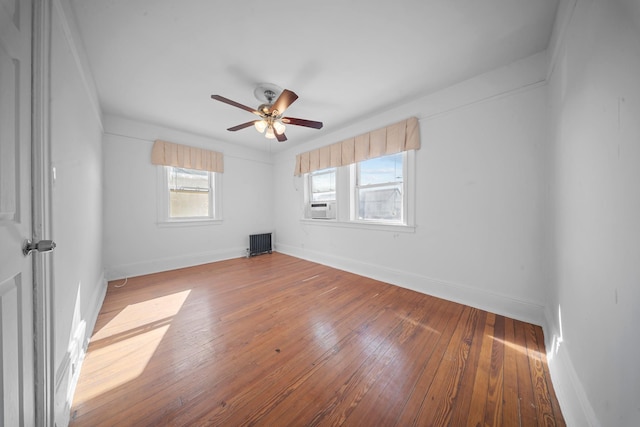 empty room featuring hardwood / wood-style flooring, radiator heating unit, and ceiling fan