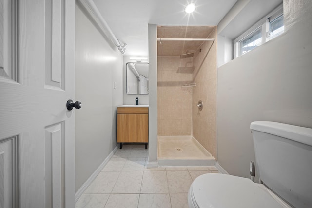 bathroom with a tile shower, vanity, tile patterned flooring, and toilet