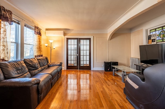 living room with hardwood / wood-style floors, an AC wall unit, and french doors