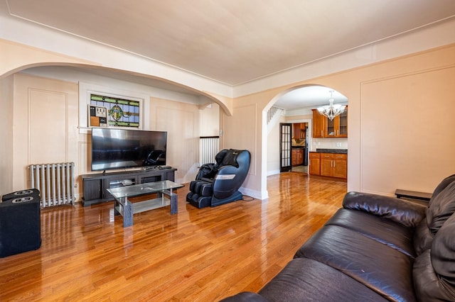 living room featuring light hardwood / wood-style floors, radiator, and a notable chandelier