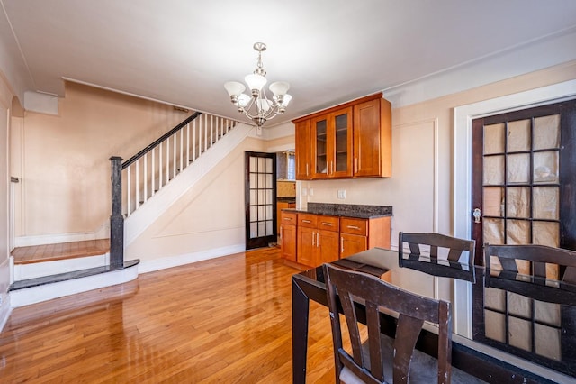 1059 Neill Ave, Bronx, NY 10461 - kitchen featuring brown cabinets, light wood finished floors, a chandelier, dark countertops, and glass insert cabinets