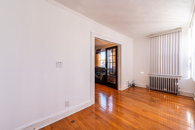 unfurnished room with crown molding, radiator heating unit, and hardwood / wood-style flooring