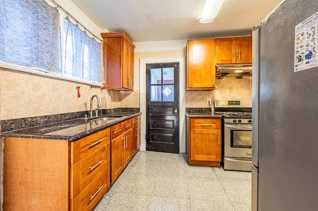 kitchen featuring appliances with stainless steel finishes, plenty of natural light, dark stone counters, and sink