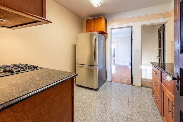 kitchen with stainless steel appliances, extractor fan, and dark stone counters