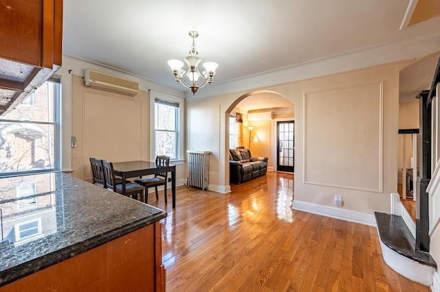 dining area with a wall mounted air conditioner, light wood-type flooring, and a chandelier