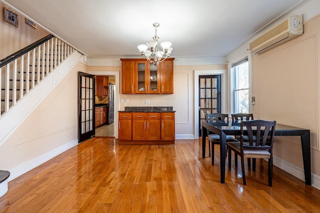 kitchen with a chandelier, decorative light fixtures, a wall mounted AC, and light hardwood / wood-style flooring