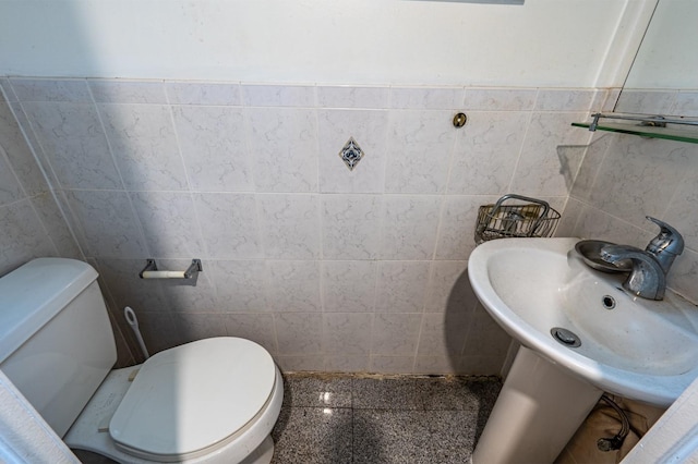 bathroom featuring sink, tile walls, and toilet