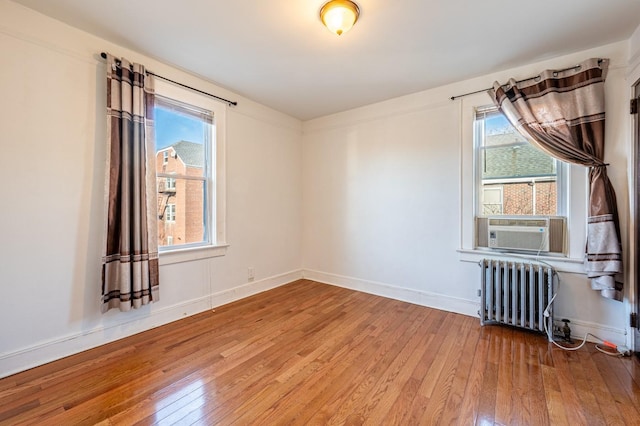 empty room featuring radiator heating unit, cooling unit, and hardwood / wood-style flooring