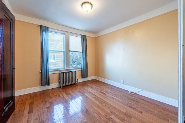 empty room with radiator heating unit and light hardwood / wood-style flooring