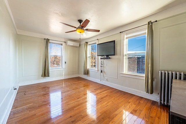 spare room with radiator, ornamental molding, a wall mounted AC, ceiling fan, and wood-type flooring