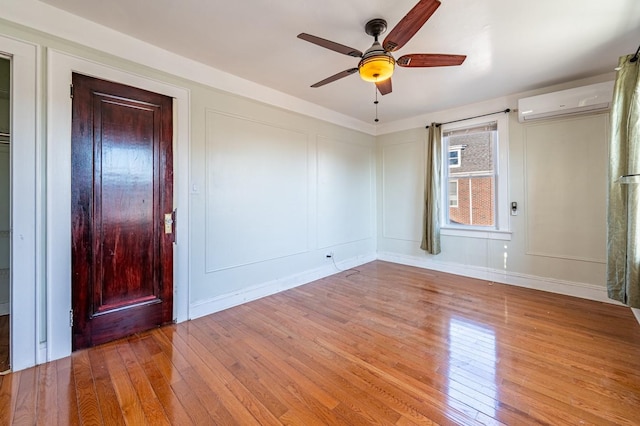 interior space featuring light hardwood / wood-style flooring, a wall unit AC, and ceiling fan