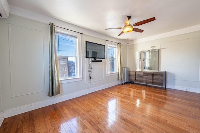 interior space featuring ceiling fan, light hardwood / wood-style floors, radiator, and multiple windows