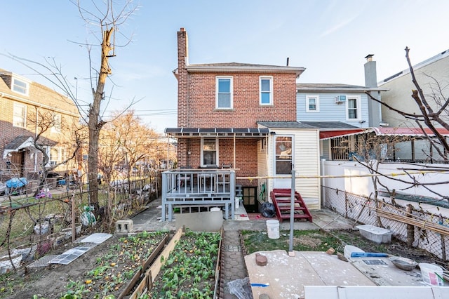 1059 Neill Ave, Bronx, NY 10461 - rear view of house featuring brick siding, a fenced backyard, a chimney, a wooden deck, and a garden