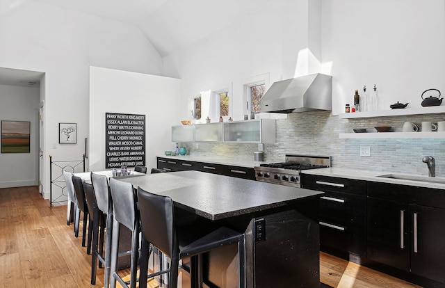 kitchen featuring sink, light wood-type flooring, a kitchen island, stainless steel range oven, and a breakfast bar area