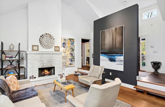 living room with a stone fireplace, wood-type flooring, and high vaulted ceiling