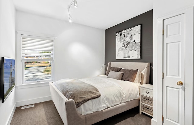 bedroom with dark colored carpet and track lighting