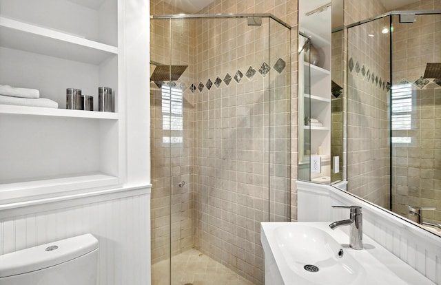 bathroom with toilet, a shower with door, and sink