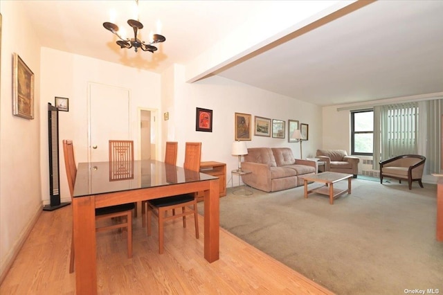 dining space with light hardwood / wood-style floors and an inviting chandelier