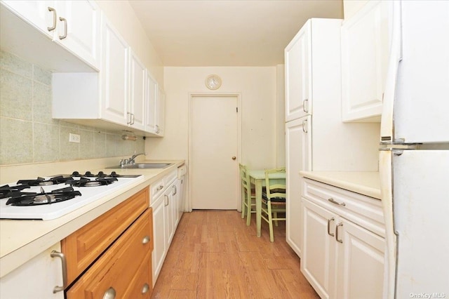 kitchen featuring light hardwood / wood-style floors, white appliances, white cabinetry, and sink