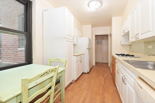 kitchen featuring white cabinets, white appliances, light wood-type flooring, and sink