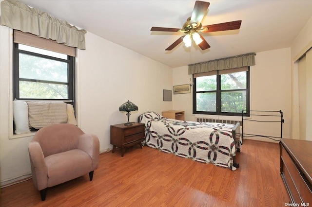 bedroom featuring ceiling fan, radiator heating unit, and light hardwood / wood-style floors