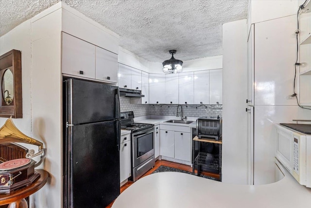 kitchen featuring electric stove, sink, white cabinetry, black fridge, and decorative backsplash