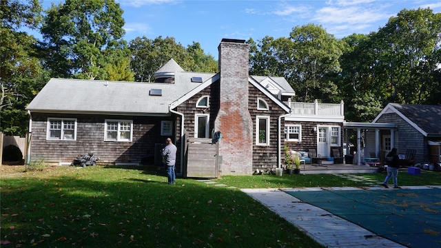 back of property featuring a yard, a patio, a balcony, and a covered pool