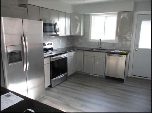 kitchen featuring appliances with stainless steel finishes, light hardwood / wood-style floors, white cabinetry, and sink